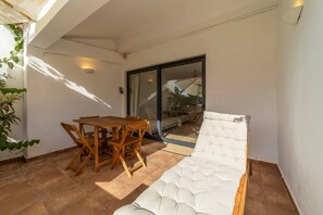 Ein Balkon mit gepolsterten Sofas, einem Holztisch und Stühlen.