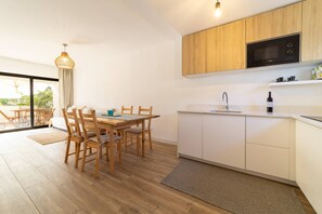 Eine moderne Küche mit Holzausbau, einer eingebauten Mikrowelle und einem Essbereich mit Tisch und Stühlen.