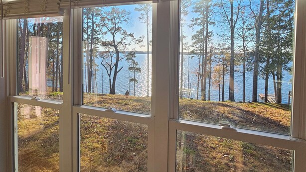 A room with a large window overlooking a lake and trees. - New lakefront 3 bedroom, 2 story house in lovely Georgetown with private dock (Georgetown)