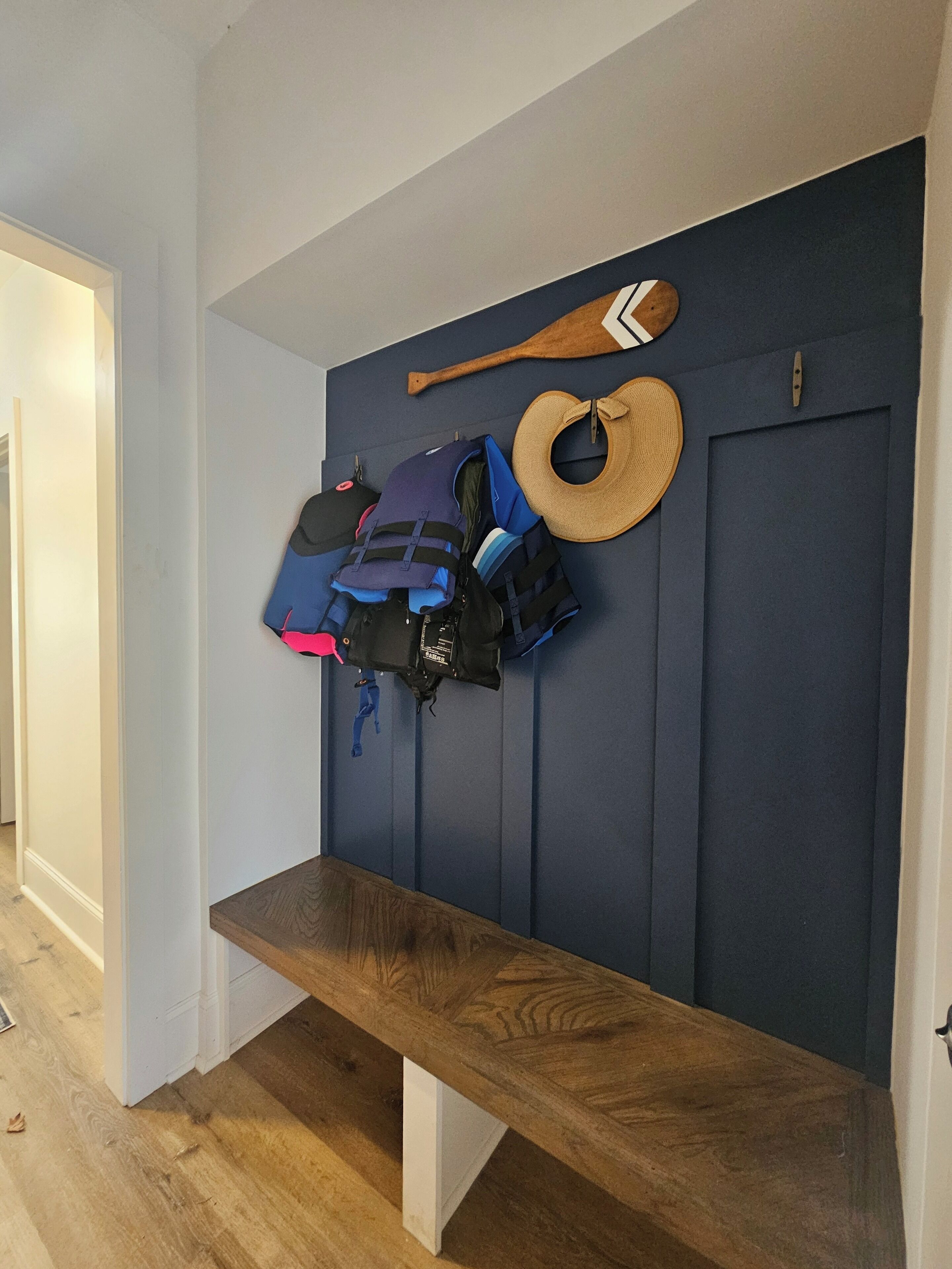 A hallway with a wooden bench, a blue wall, and a door.