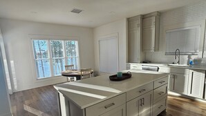 A modern kitchen with a large island, white cabinetry, and a wooden floor. - New lakefront 3 bedroom, 2 story house in lovely Georgetown with private dock (Georgetown)