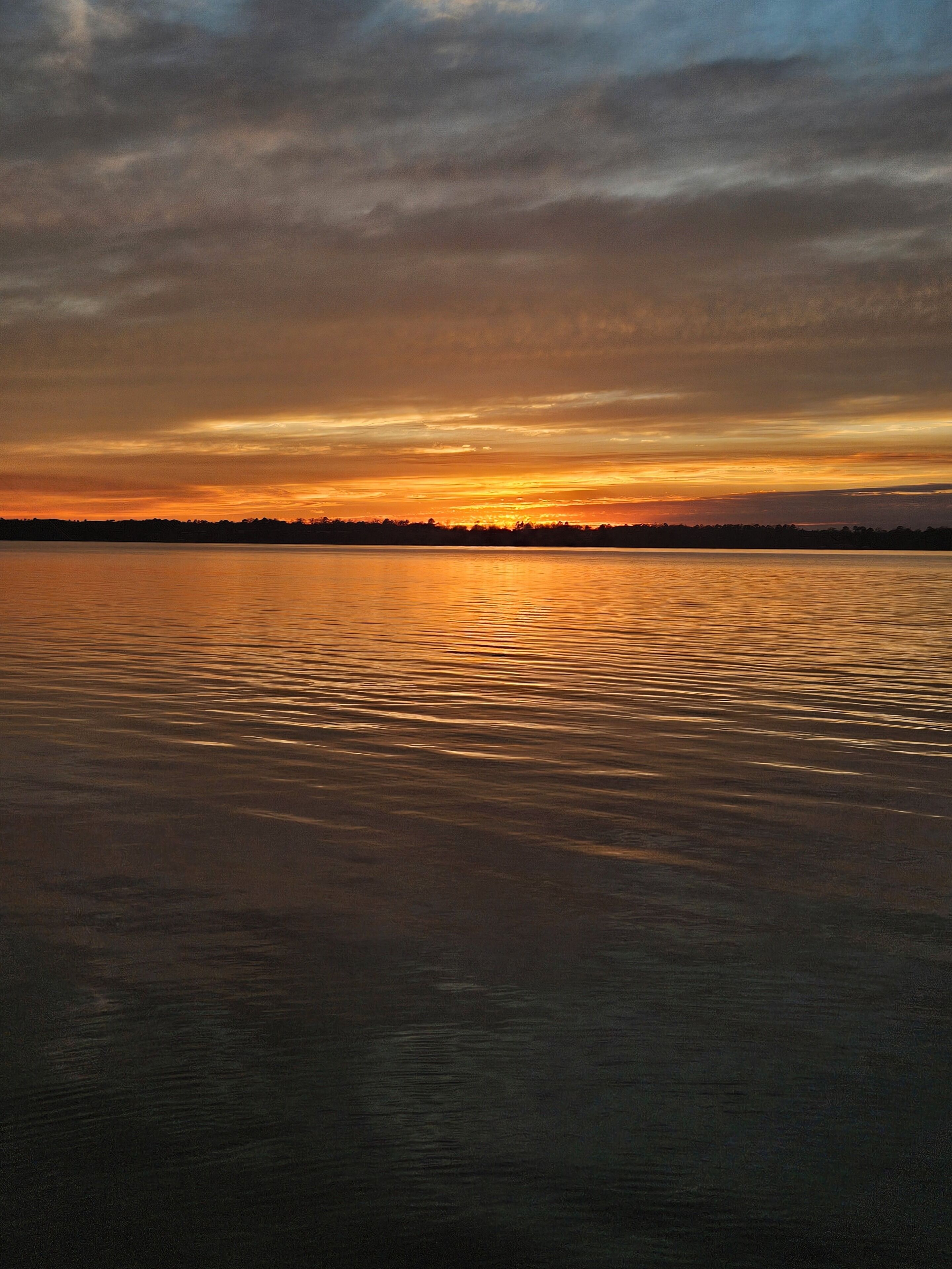 Ruhige Wasserfläche, die den Sonnenuntergang spiegelt.