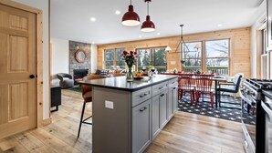 Una cocina moderna con una isla central, suelo de madera y ventanas amplias.