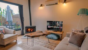 Un salon chaleureux avec un canapé, un téléviseur, une cheminée et un plafond en bois.