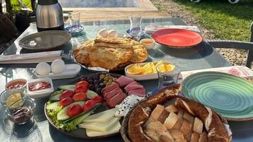 Un espace de restauration en plein air avec une table dressée pour un repas, comprenant du pain, des œufs et des légumes.