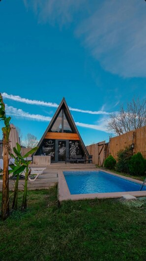 A modern house with a triangular roof, a pool, and a wooden deck. - BUNGOVİLLA RESORT HOTEL (Sapanca)