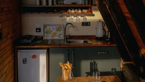 Une cuisine compacte aux murs en bois, avec un petit réfrigérateur et une table à manger pour deux personnes.