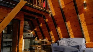 Une chambre mansardée chaleureuse, avec un espace nuit en mezzanine, des poutres apparentes et une esthétique rustique.