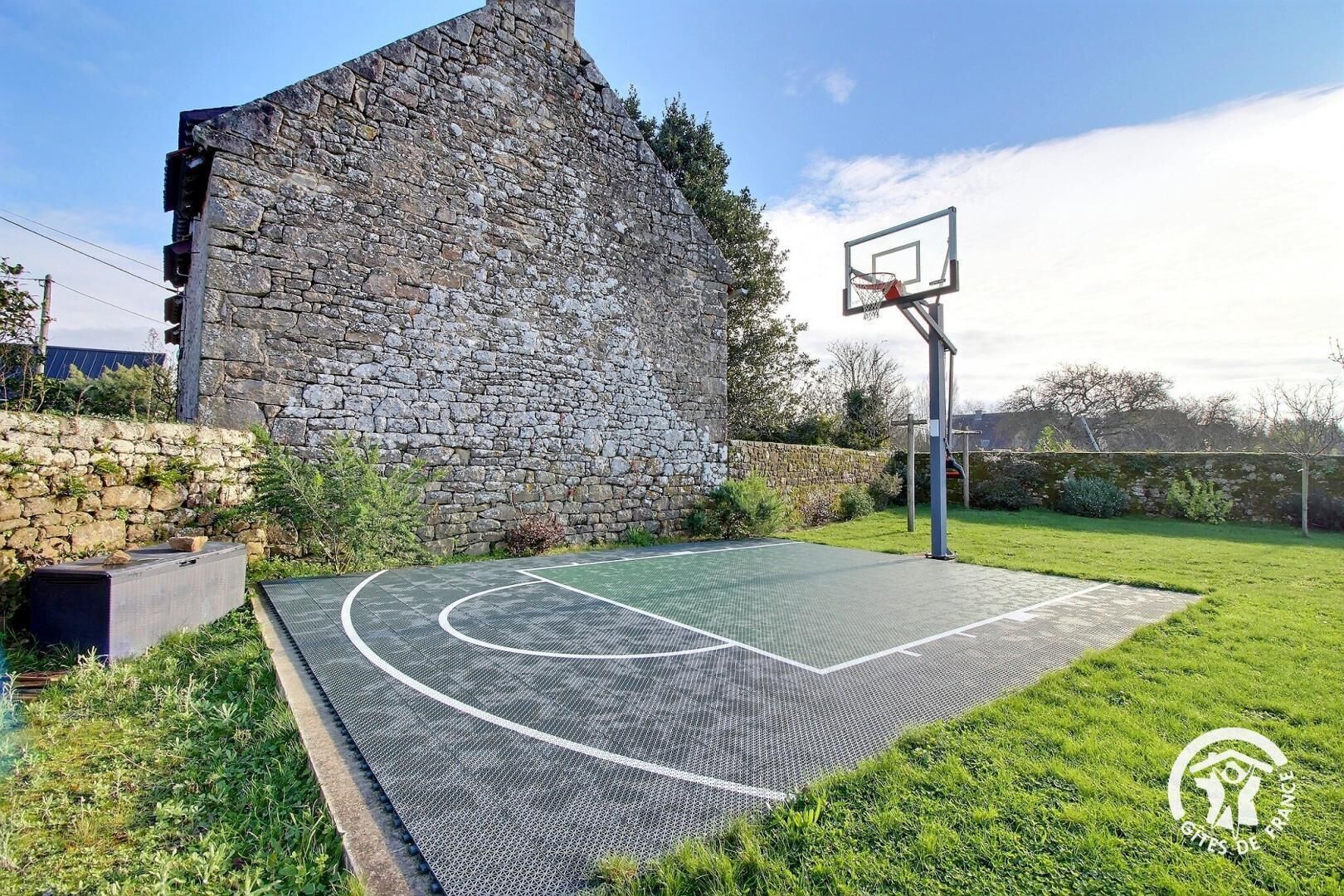 A basketball court with a stone wall and a basketball hoop.