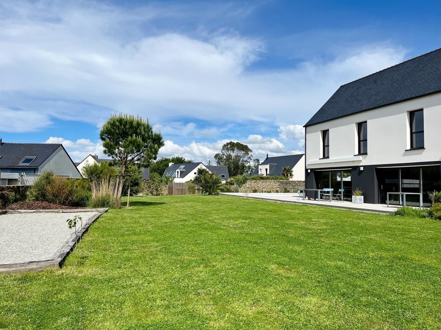 A modern residential area with houses, a well-maintained lawn, and a clear sky.