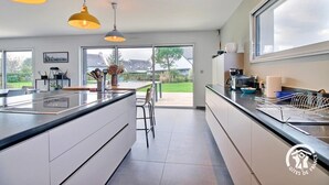 Una cocina moderna con una isla grande, luces colgantes y vistas al exterior.