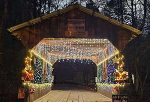 A wooden covered bridge decorated with lights and nutcracker figures. - Romantic Cabin + Hot Tub + Firepit (Ellijay)