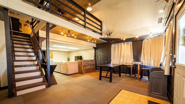 Amplia habitación tipo loft con escaleras, zona de comedor y un rincón de estar acogedor.