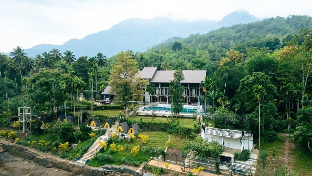 A resort with multiple buildings, a swimming pool, and lush greenery.