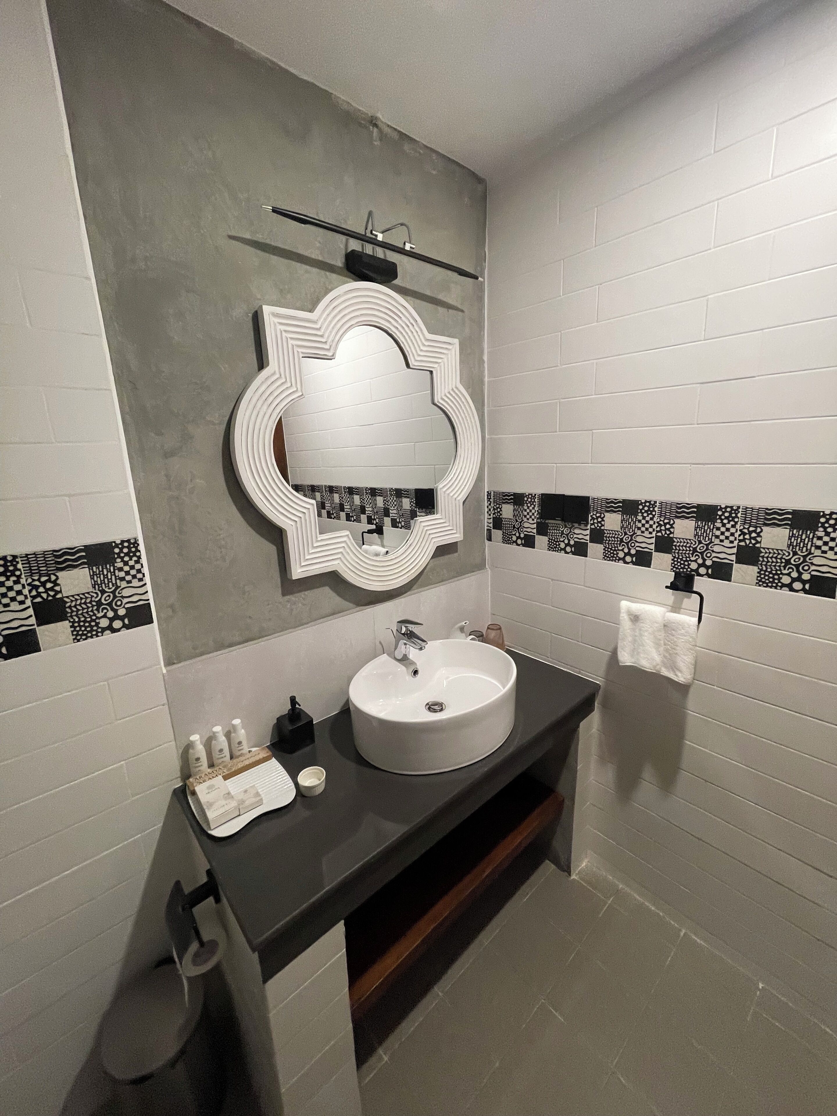 A bathroom with a round sink, a mirror with a decorative frame, and a towel hanging on a rack.