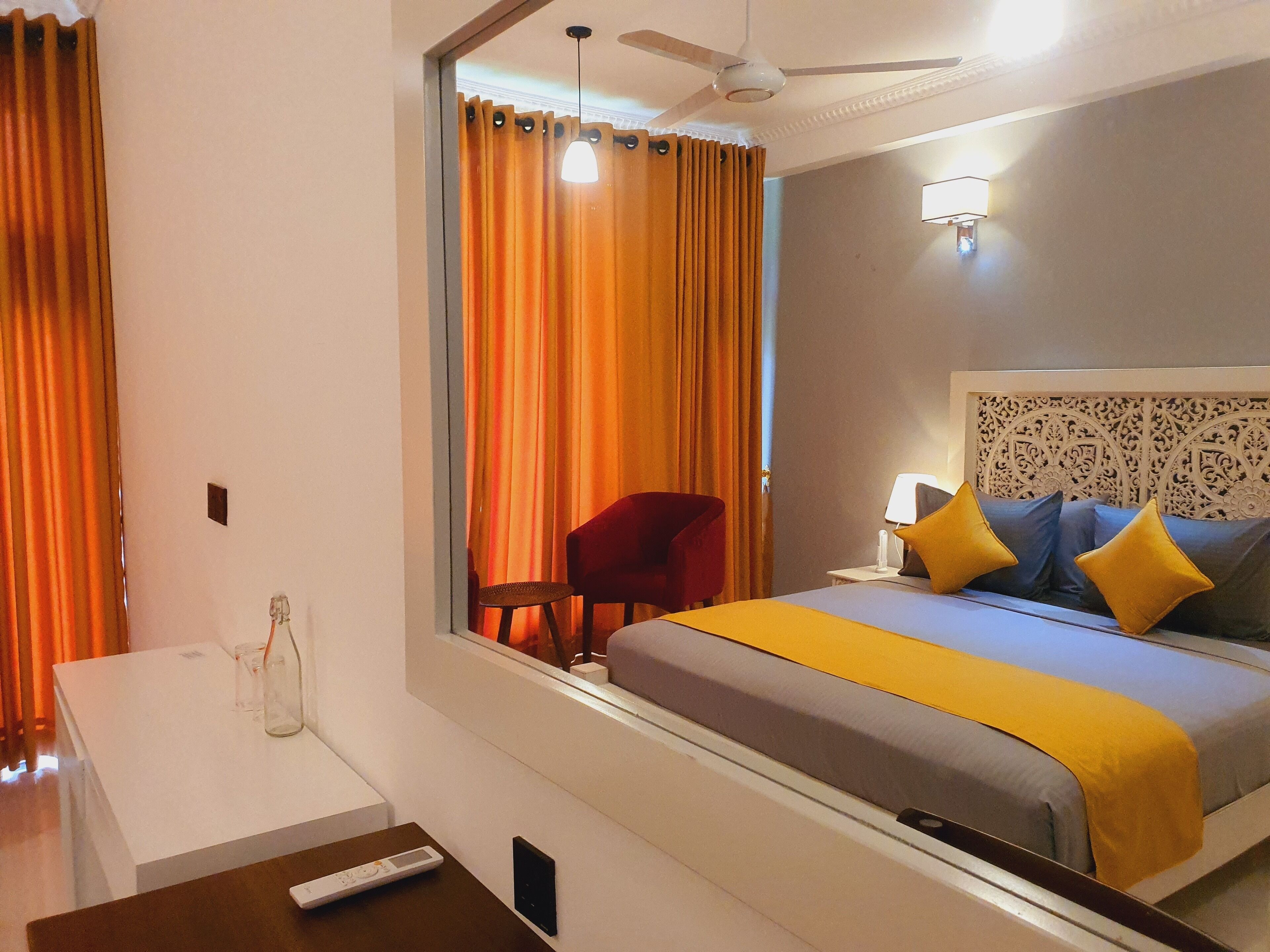 A hotel room with a bed, a desk, a chair, and a mirror.