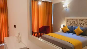 A hotel room with a bed, a desk, a chair, and a mirror.