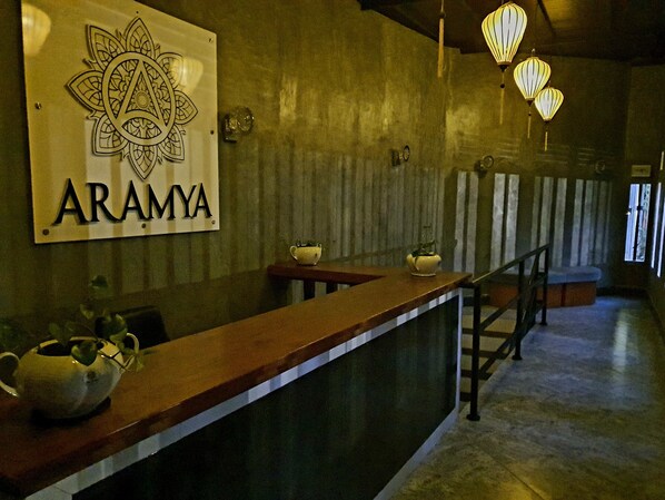 A reception area with a wooden counter, a sign reading "ARAMYA," and hanging lanterns. - Aramya hotel (Kitulgala)