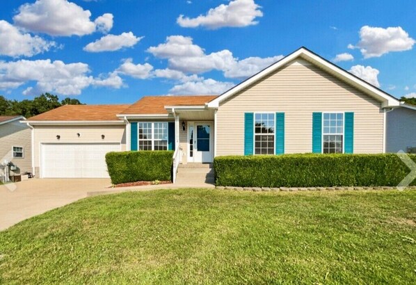 A single-story house with a front garage, a covered porch, and a well-maintained lawn.