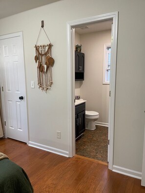 A bathroom with a toilet, a sink, and a cabinet. There is a door leading to another room.