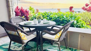 Une table ronde entourée de chaises, avec vue sur la mer et agrémentée de plantes en pot.