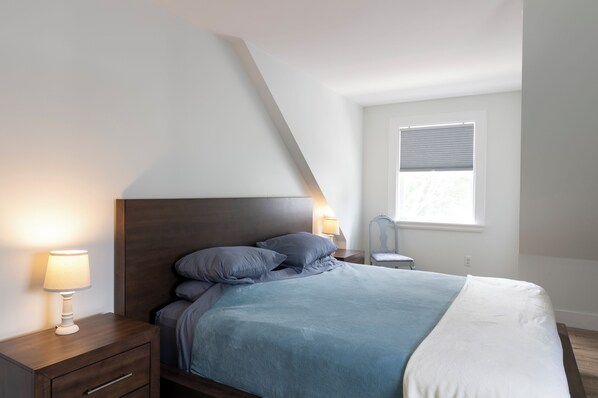 A bedroom with a bed, nightstands, and a window.