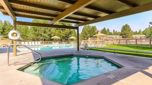 Una piscina cubierta al aire libre con terraza de madera, sillas de descanso y sombrillas.