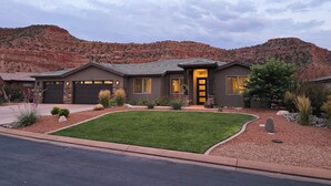 A modern two-story house with a stone facade, a well-manicured lawn, and a mountain backdrop. - Guest favorite near Zion/Epic view/Pickleball/Pool (Kanab)