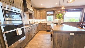 A modern kitchen with stainless steel appliances, wooden cabinets, and a large island. - Guest favorite near Zion/Epic view/Pickleball/Pool (Kanab)