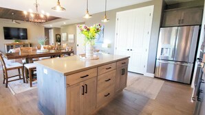 A modern kitchen with a central island, stainless steel appliances, and a dining area with a fireplace. - Guest favorite near Zion/Epic view/Pickleball/Pool (Kanab)