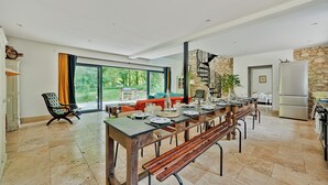A spacious dining area with a long table set for a meal, a comfortable seating area with a sofa, and a kitchen area with a refrigerator.