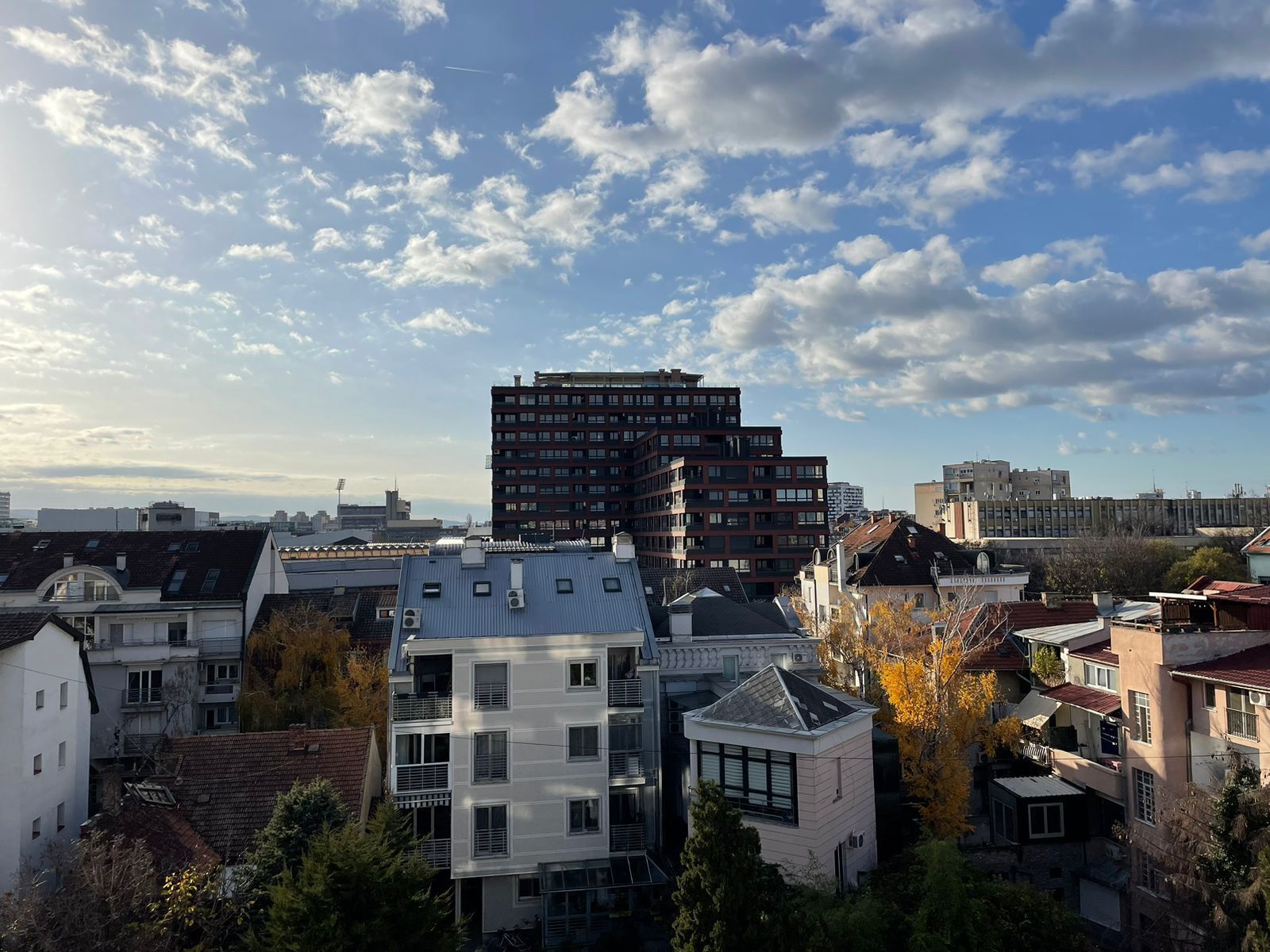 A multi-story building with a modern architectural design, surrounded by other residential buildings.