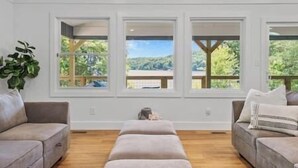 Une pièce dotée de trois grandes fenêtres, d’un plancher en bois et de deux canapés.