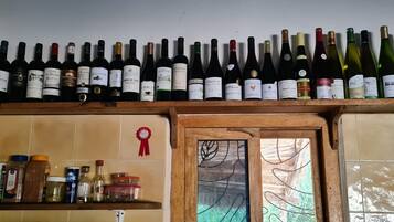 Une cuisine avec une étagère en bois où sont rangées différentes bouteilles de vin et divers ustensiles de cuisine.