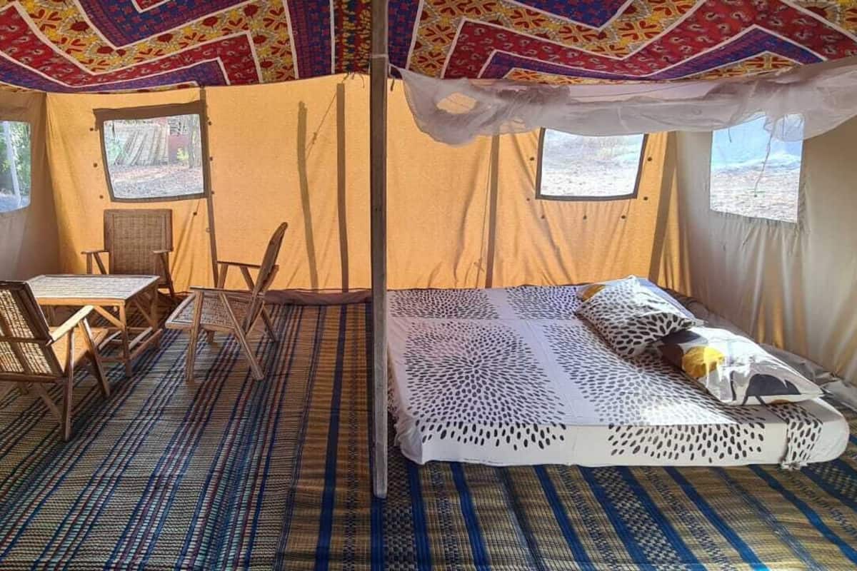 A tent with a bed, a table, and chairs.