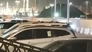 Een parkeerplaats met auto's en straatverlichting in de nacht.