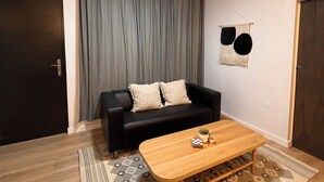A modern living room with a black leather sofa, a wooden coffee table, a ceiling fan, and a patterned rug. - Sol y Mar - Oceanfront Condo! (Cabo Rojo)