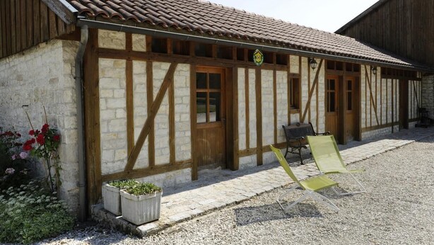 A traditional half-timbered building with a tiled roof, a wooden door, and a small outdoor seating area with chairs. - Le Cellier aux Moines (COLOMBE LE SEC)