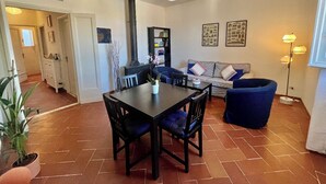 Un salon comprenant une table à manger, un canapé bleu et une bibliothèque noire.