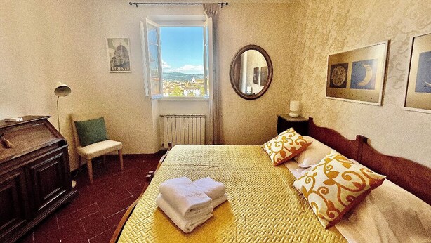 Une chambre d’hôtel avec un lit, une chaise, un bureau et une fenêtre donnant sur un paysage agréable.