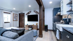 A modern living room with a grey sofa, a coffee table, and a TV mounted on the wall.