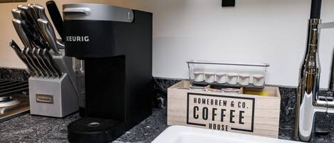A kitchen with a Keurig coffee maker, a knife block, and a coffee service box labeled "Homebrew & Co. Coffee House".