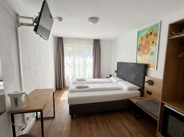 A hotel room with a bed, a desk, a television mounted on the wall, and a painting on the wall. - Hotel Hechtplatz (Self Check-In) (Zürich)