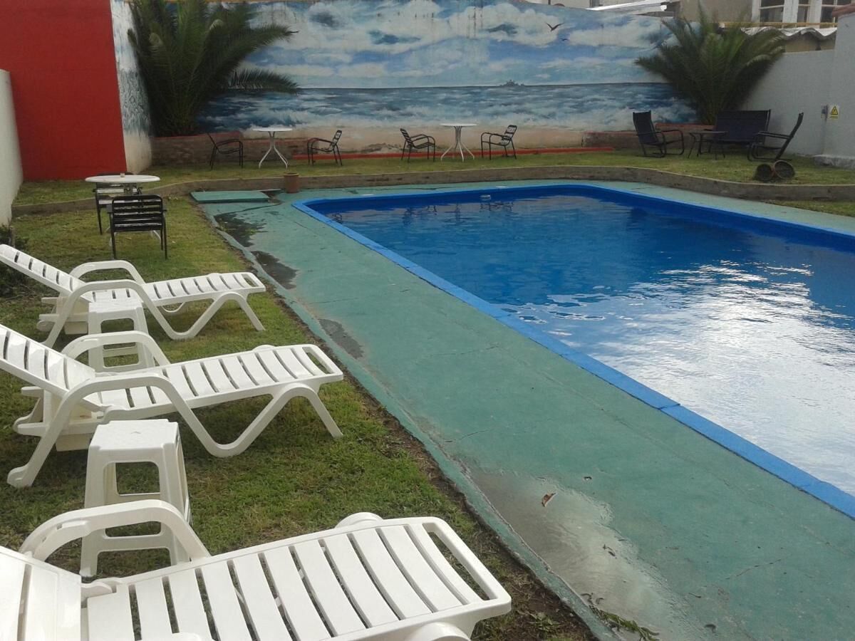 Una piscina con sillas de descanso y un mural que representa una playa.