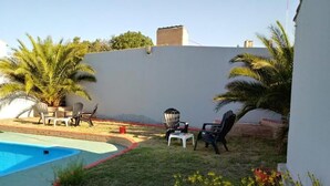 A backyard with a swimming pool, outdoor seating, and palm trees. - Buenavista Hotel (La Falda)