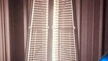 Uma luminária de chão alta e estreita, com estrutura de metal, base quadrada e cúpula cônica.