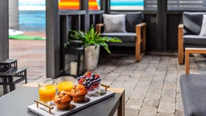 A breakfast setup with a tray of muffins, a bowl of mixed berries, and glasses of orange juice on a table.