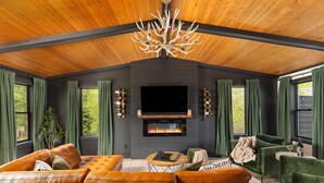 A cozy living room with a fireplace, leather sofa, and green curtains.