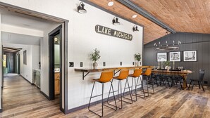 A modern bar area with a 'Lake Michigan' sign, wooden bar counter, and bar stools.