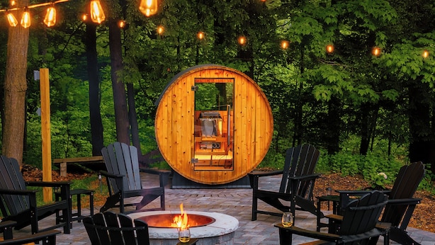 A circular wooden structure with a fire pit in the center, surrounded by black Adirondack chairs and a brick patio.